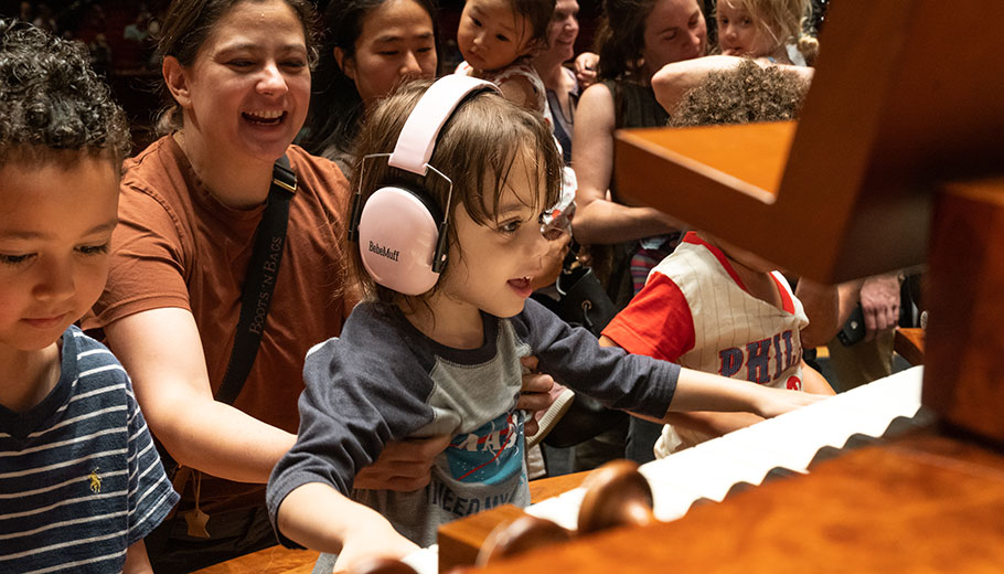 a smiling woman holds a young child trying the organ at the Kimmel Center