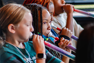 Close up of children playing band instruments.