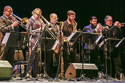Jazz musicians - two trombones, saxophone, two trumpets on stage playing 
