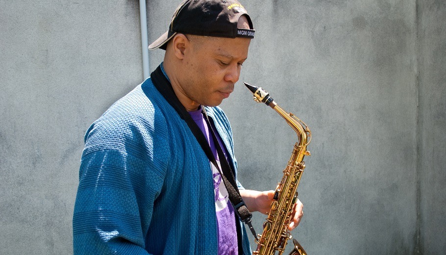 Steve Coleman Stands with alto saxophone looking down