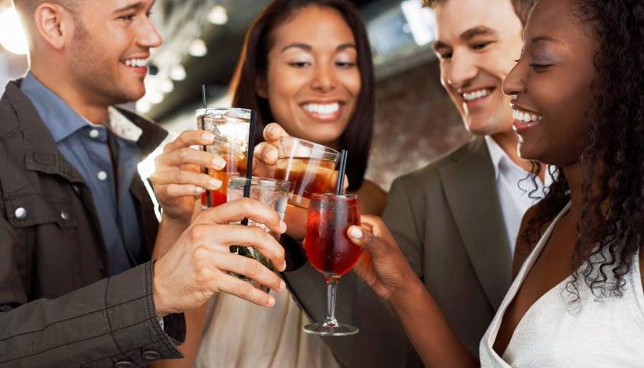 A group of smiling young adults holding up drinks