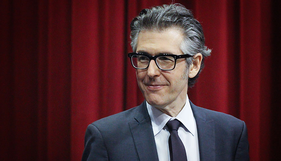 Ira Glass standing in front of a red curtain