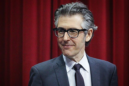 Ira Glass standing in front of a red curtain