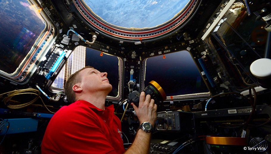 Terry Verts Looks at Earth from a spacecraft holding his camera