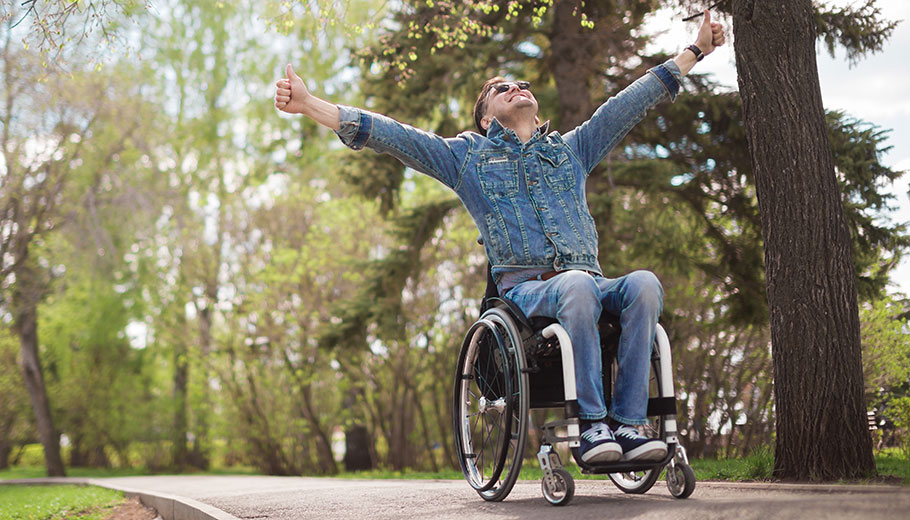 Man in wheelchair excited with hands in the air in the park