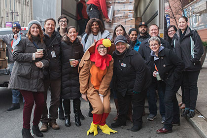 Group stands posed in front of the Kimmel Center with a truck of turkeys getting dropped off