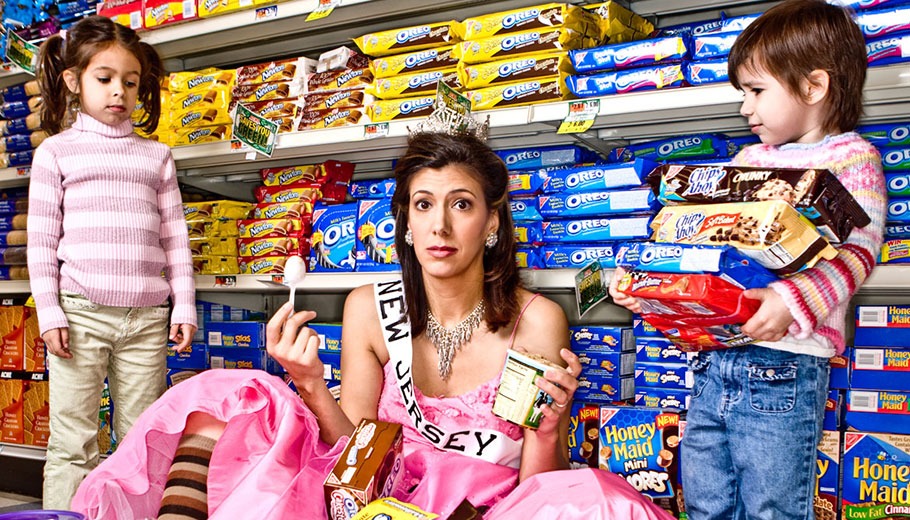 Dena Blizzard pictured in a dress among a mess of groceries with two children standing next to her