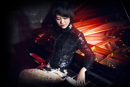 Musician Yuja Wang posing with a piano.